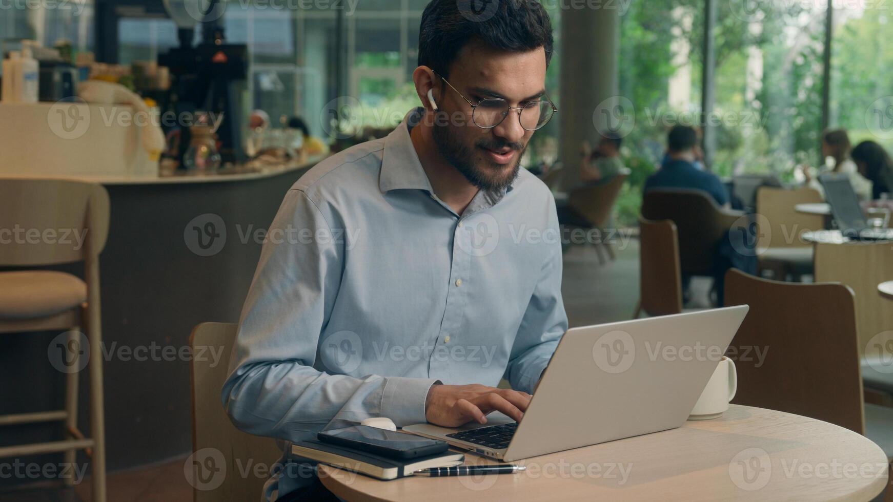 Arabian Indian man typing laptop keyboard concentrated business guy male businessman at cafe table online work computer browsing internet write tasks thinking freelancer manager employee distant study photo