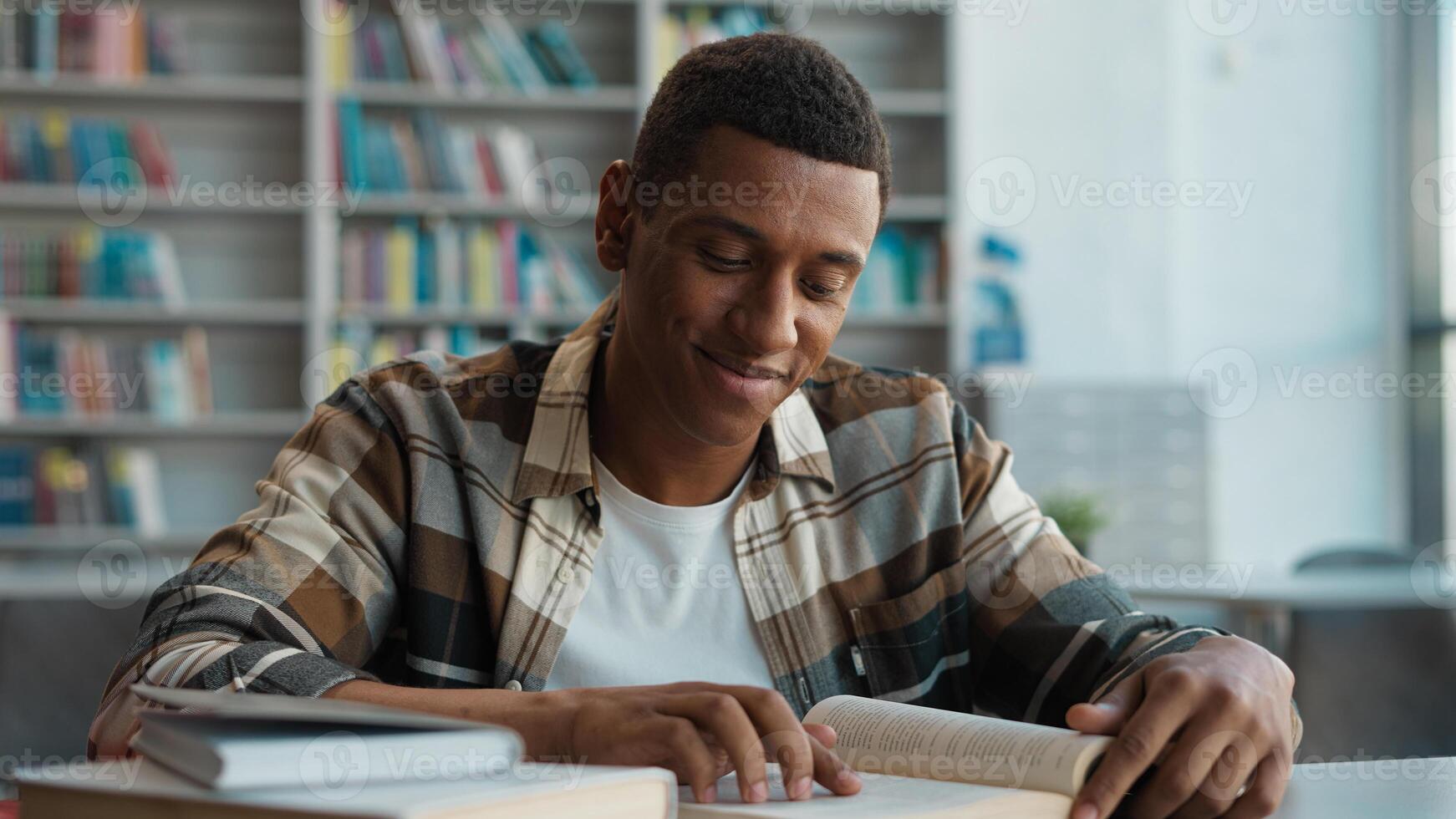 African American man bookworm reader library reading book smiling leisure student learning educational studying intelligence pleasure male guy smart literature page engaged textbook college exam novel photo