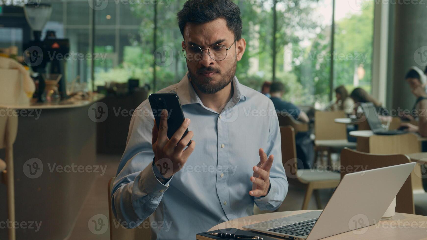 Arabian man ethnic guy upset worried frustrated businessman male business employer worker freelancer visitor reading mobile phone screen receive bad message cellphone notification sad anxious in cafe photo