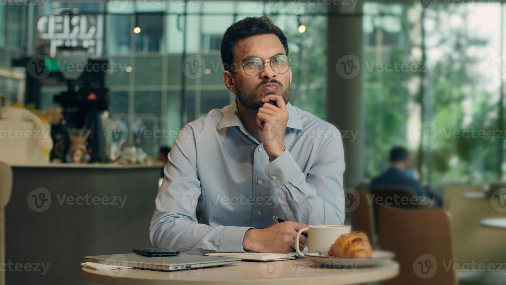 Pensive man Indian Arabian businessman male freelancer worker thoughtful student think plan create study write notebook in cafe pondering business guy inspiration idea thinking insight ponder consider photo