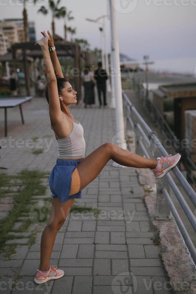 A woman is stretching outdoors by the beautiful coast, enjoying the scenic view and the fresh air photo