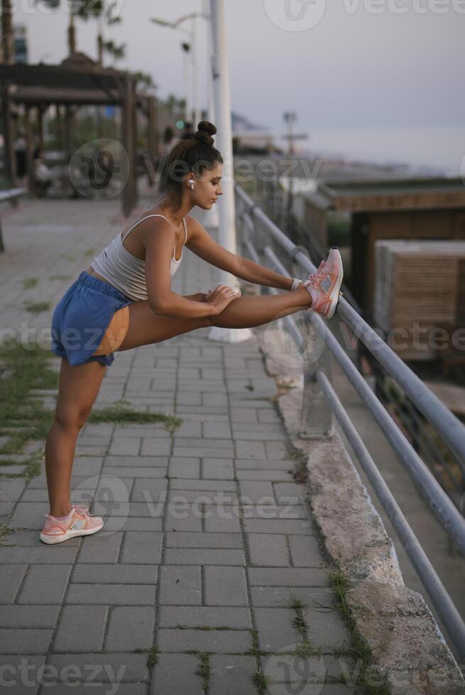 A woman is stretching gracefully by the waterfront as the evening sets in beautifully photo
