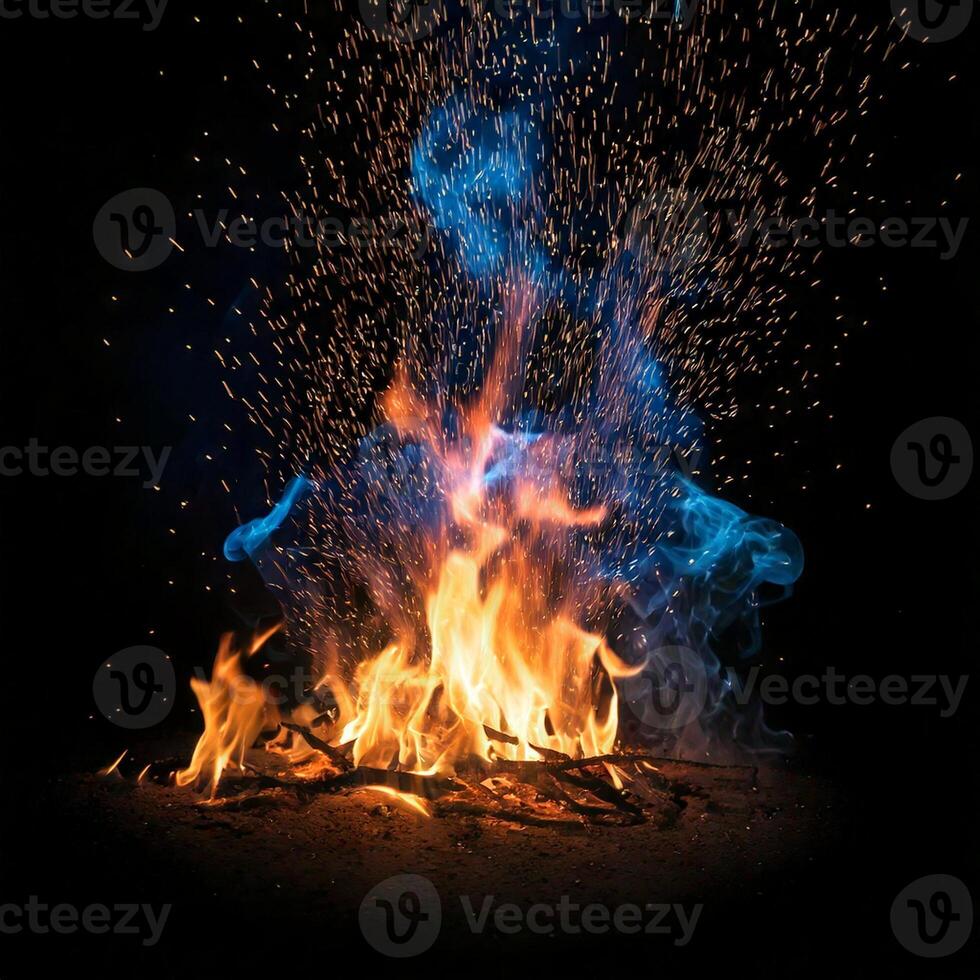 Fire burning in a black background with smoke and blue sparks photo
