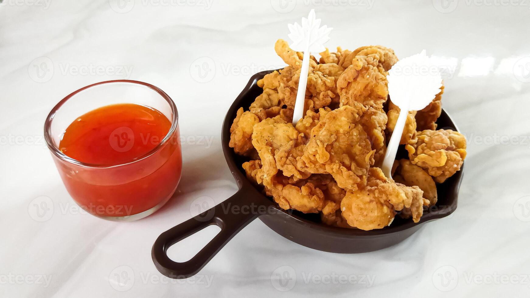 A delicious bowl of crispy fried chicken tenders served with a side of tangy dipping sauce. photo
