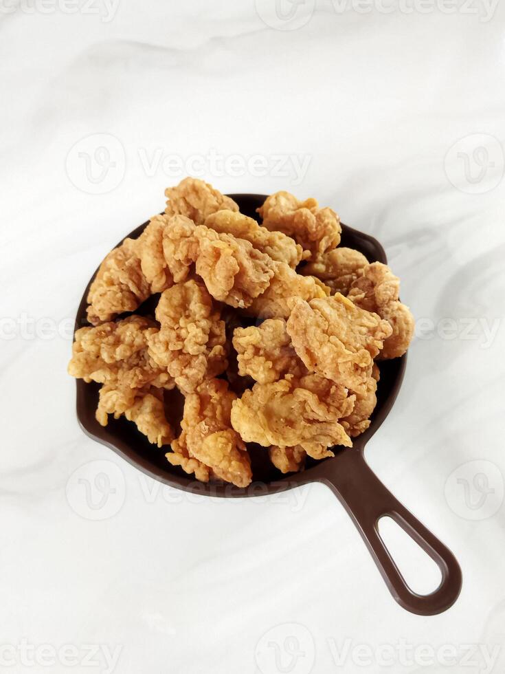 Heap of crispy fried chicken in a brown plate, isolated on white background with copy space. Close-up view photo