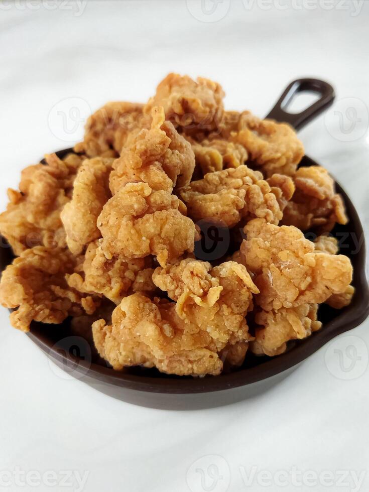 Heap of crispy fried chicken in a brown plate, isolated on white background with copy space. Close-up view photo