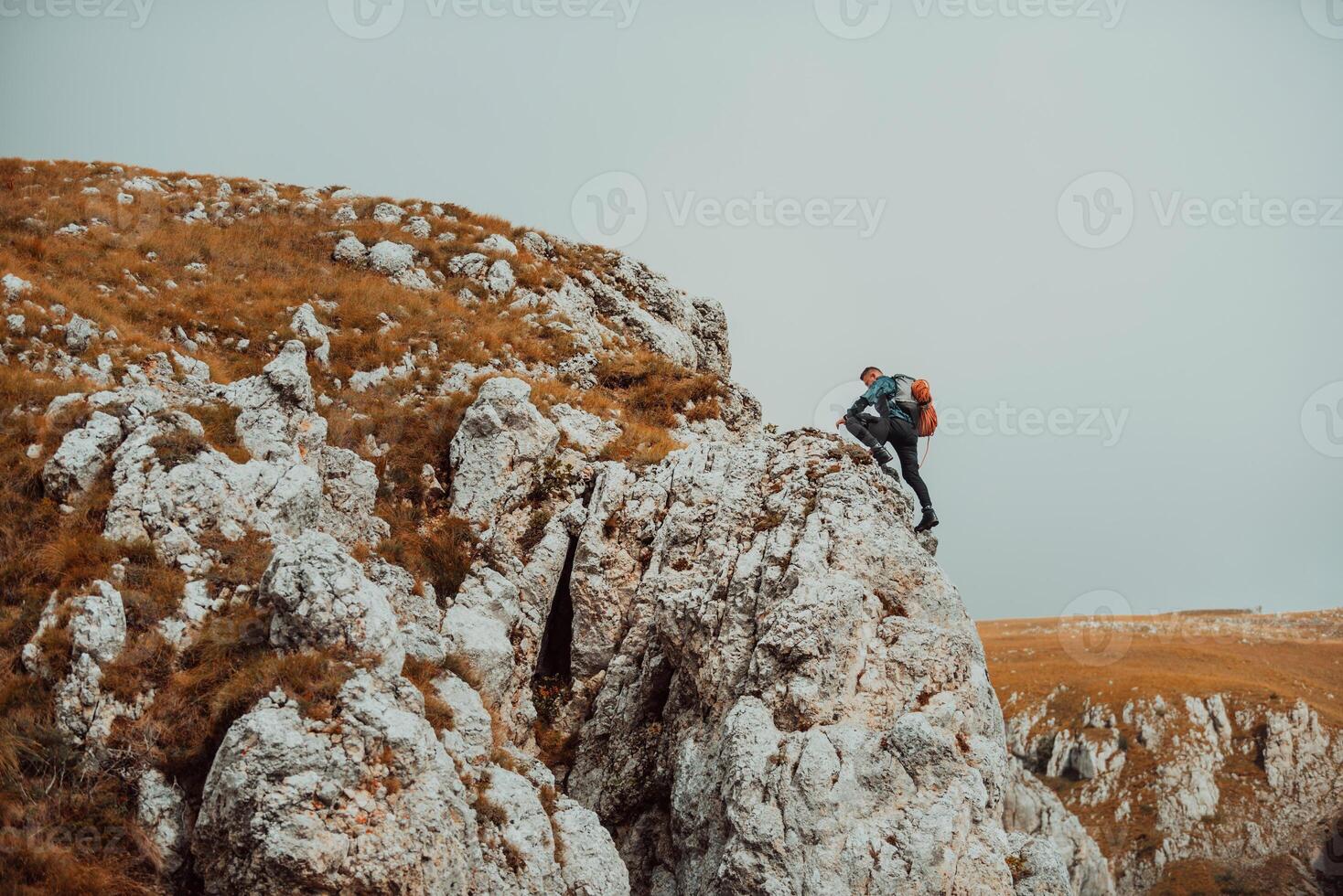A male climber climbing up on the mountain rock cliff adventure travel, extreme sport outdoor. photo
