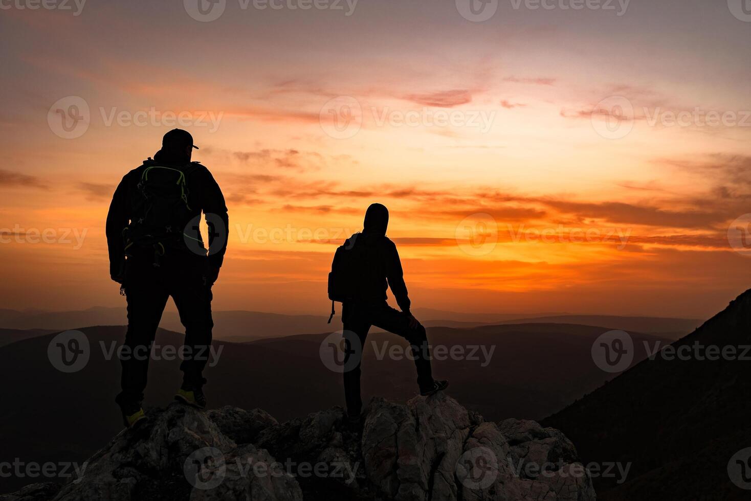 A two travelers who hikers enjoys a break look at the top of the rocky mountain during the hike. Adventure travel photo