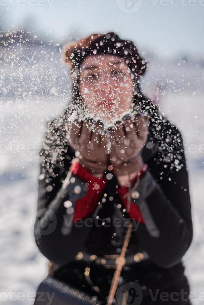 A young woman blowing a snowflakes to the camera. Winter holiday. photo