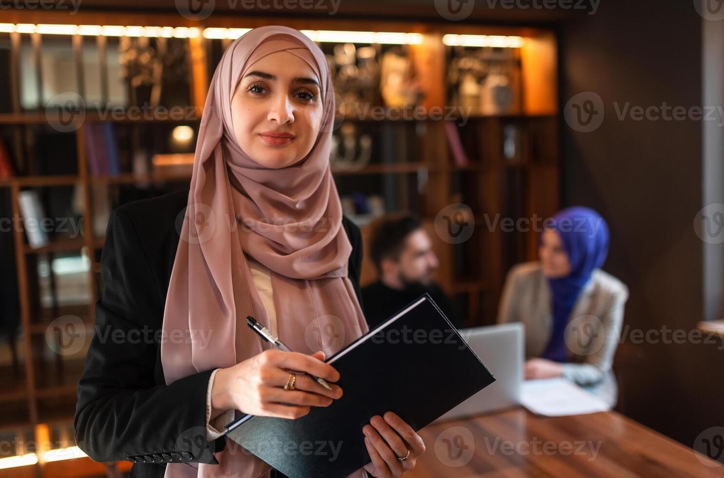 Portrait of a happy Muslim business woman front the working team in the office. photo