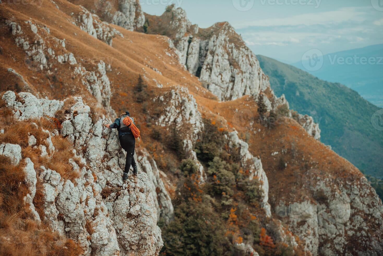A male climber climbing up on the mountain rock cliff, adventure travel, adrenaline extreme sport outdoor. photo