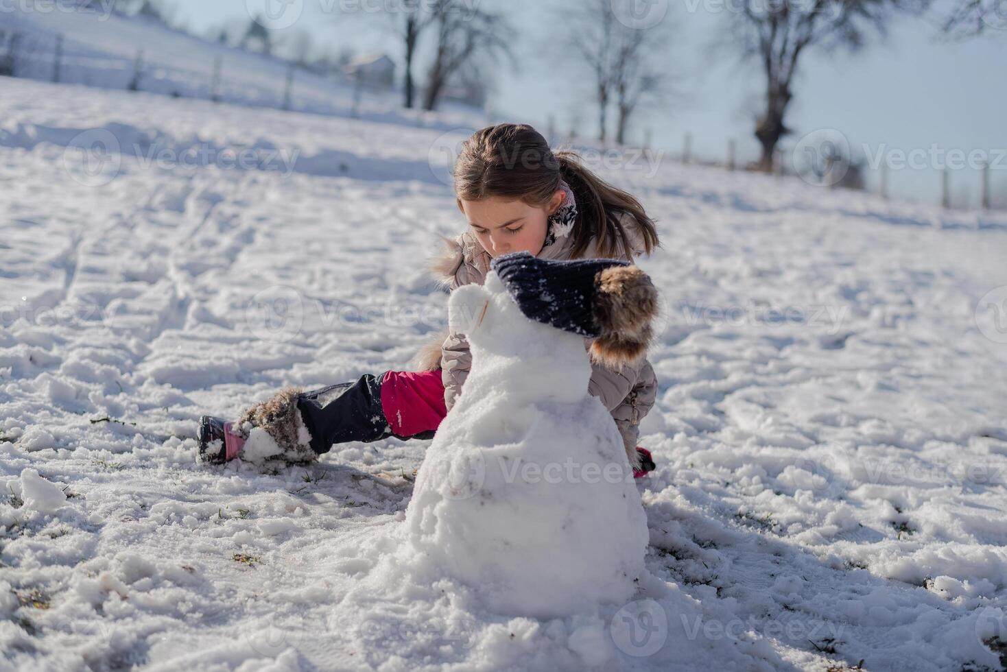 A child playing in the snow building a snowman. photo