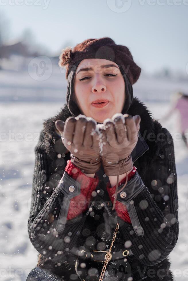 A young woman blowing a snowflakes to the camera. Winter holiday. photo