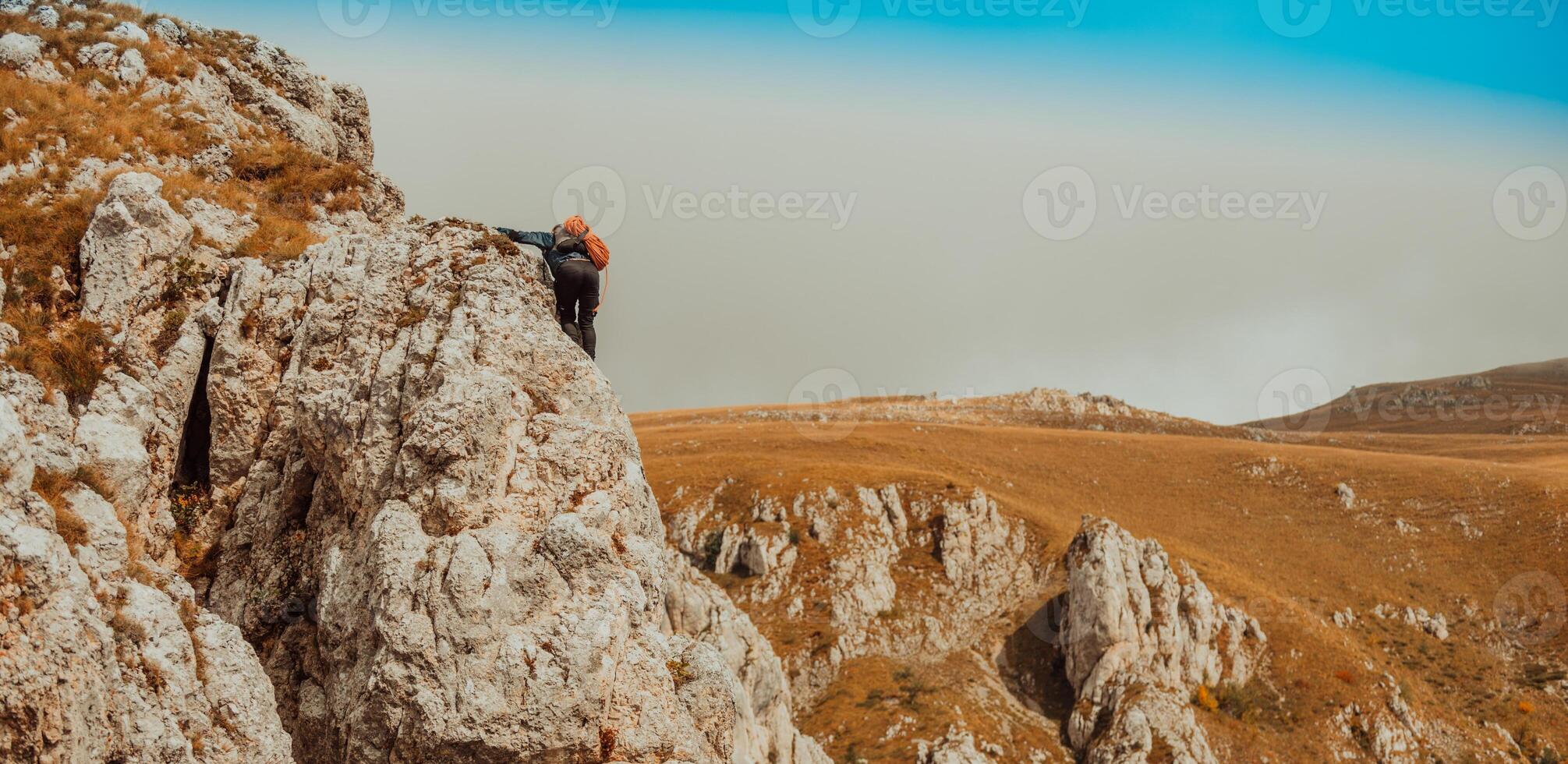 A male climber climbing up on the mountain rock cliff adventure travel, extreme sport outdoor. photo