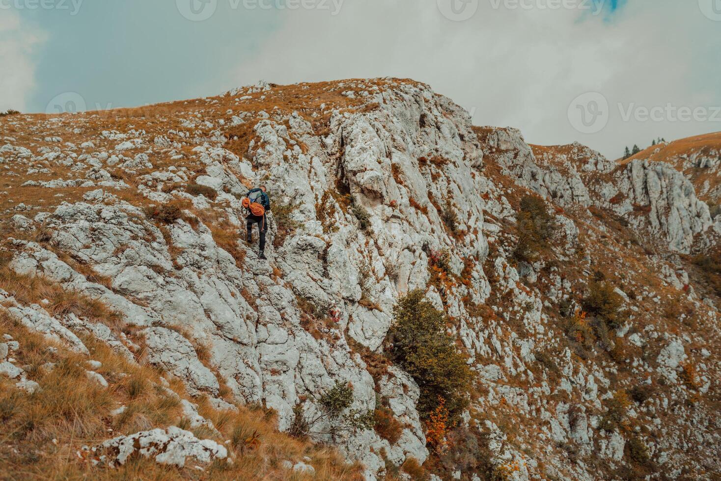 A male climber climbing up on the mountain rock cliff adventure travel adrenaline extreme sport outdoor. photo