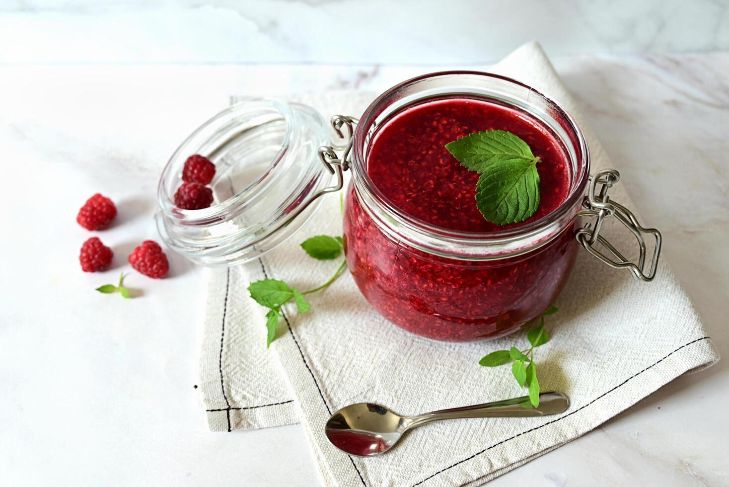 raspberry jam in a glass jar on a white background, tea with raspberries, vitamins for the body photo