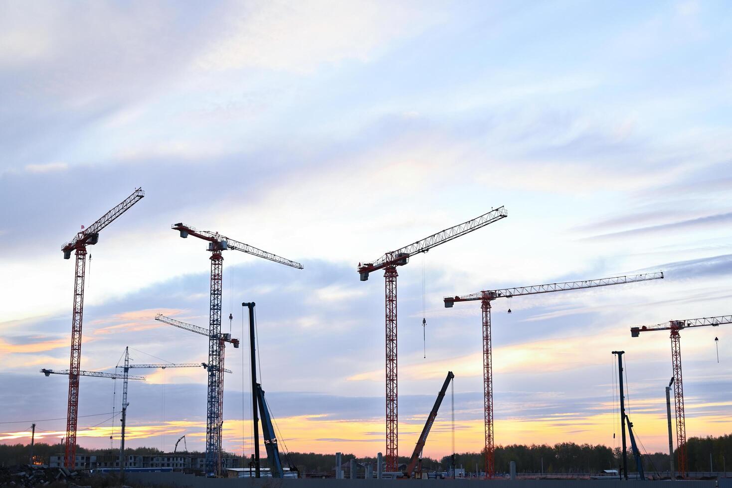 Panoramic image of a cluster of construction cranes at the initial stage of construction. Natural light photo