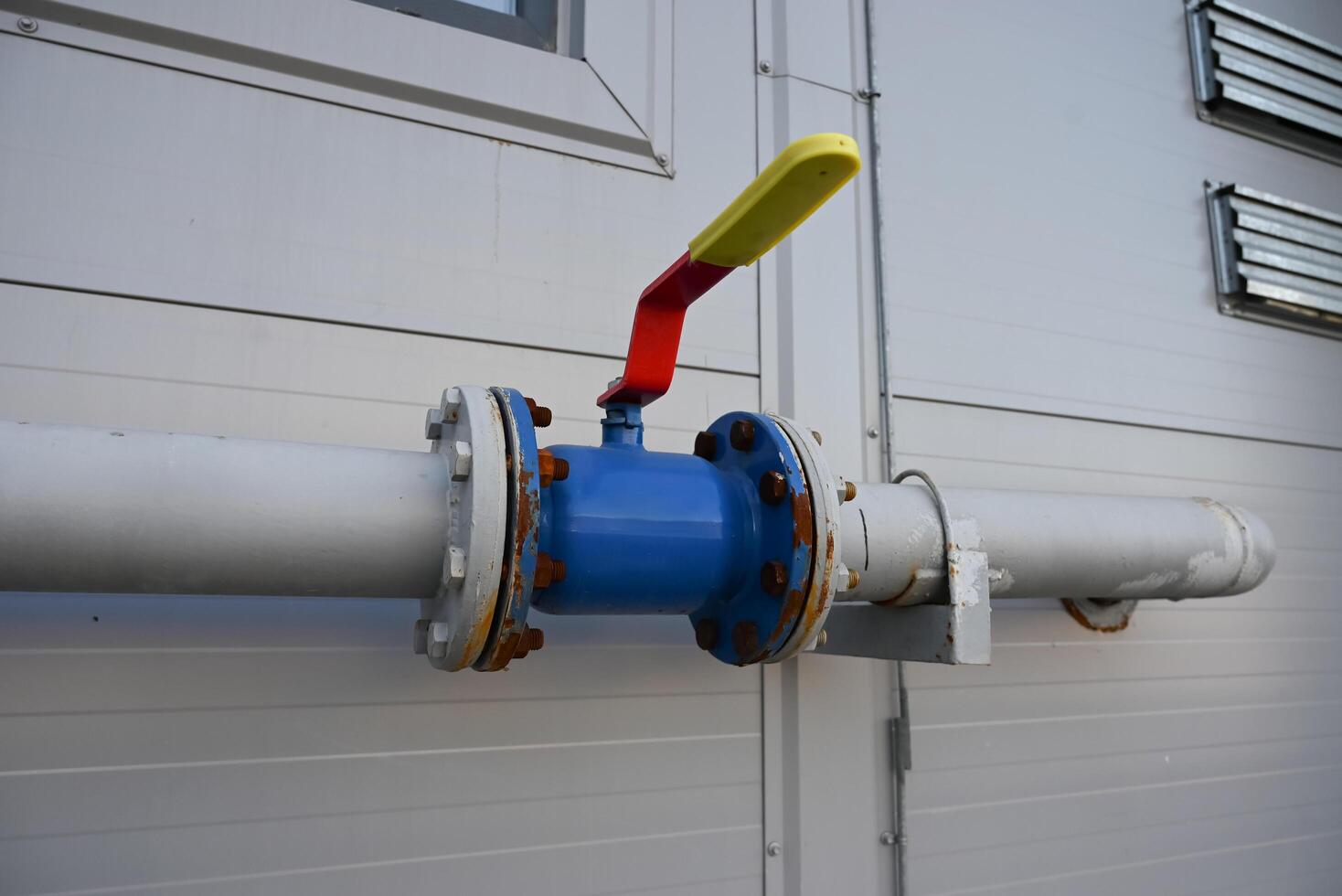 blue gas pipe with a crane goes along the facade of a new multi-storey building. House connected to gas for domestic use photo