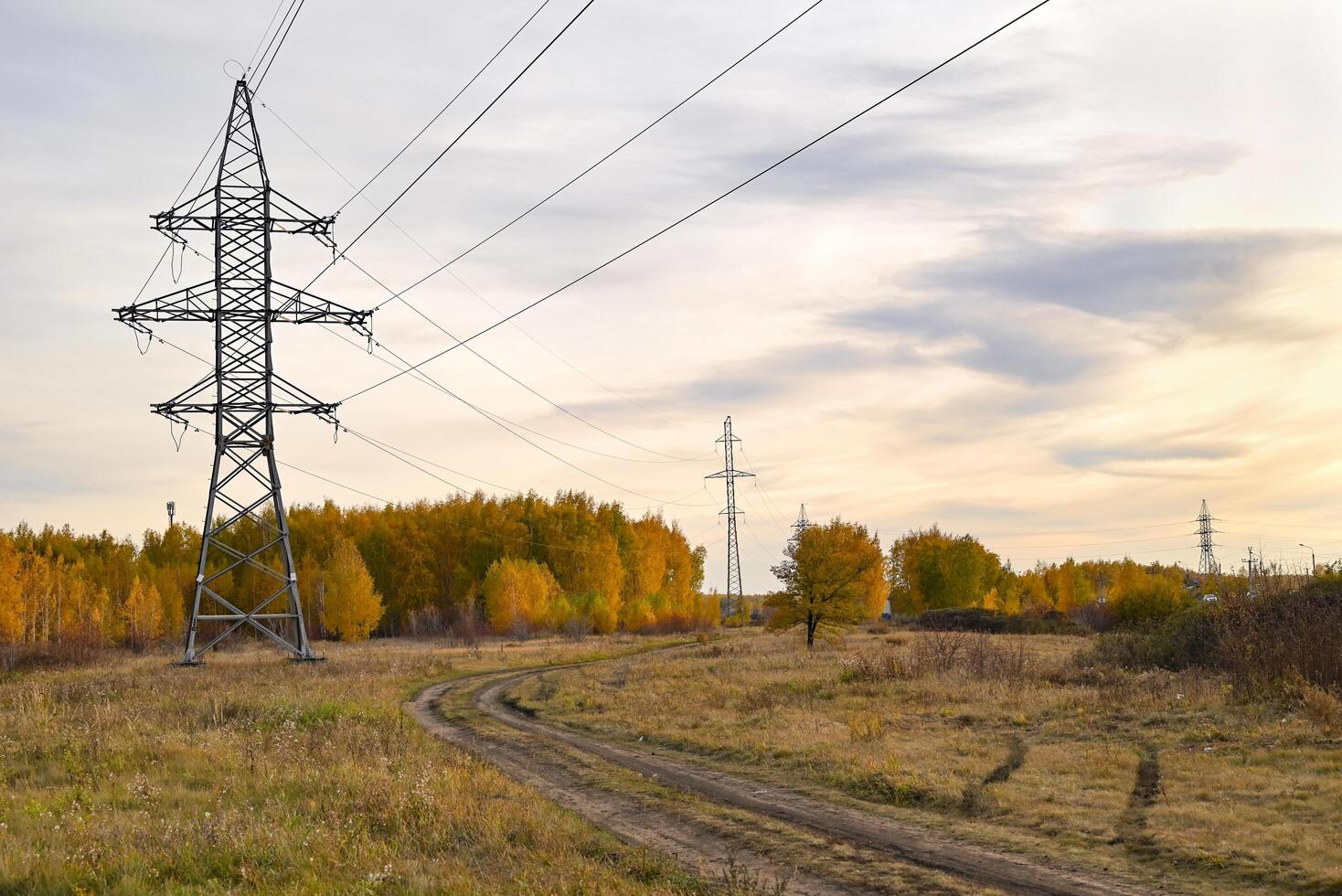 High-voltage power lines passing through a plowed field, on the background of a beautiful cloudy sky. photo