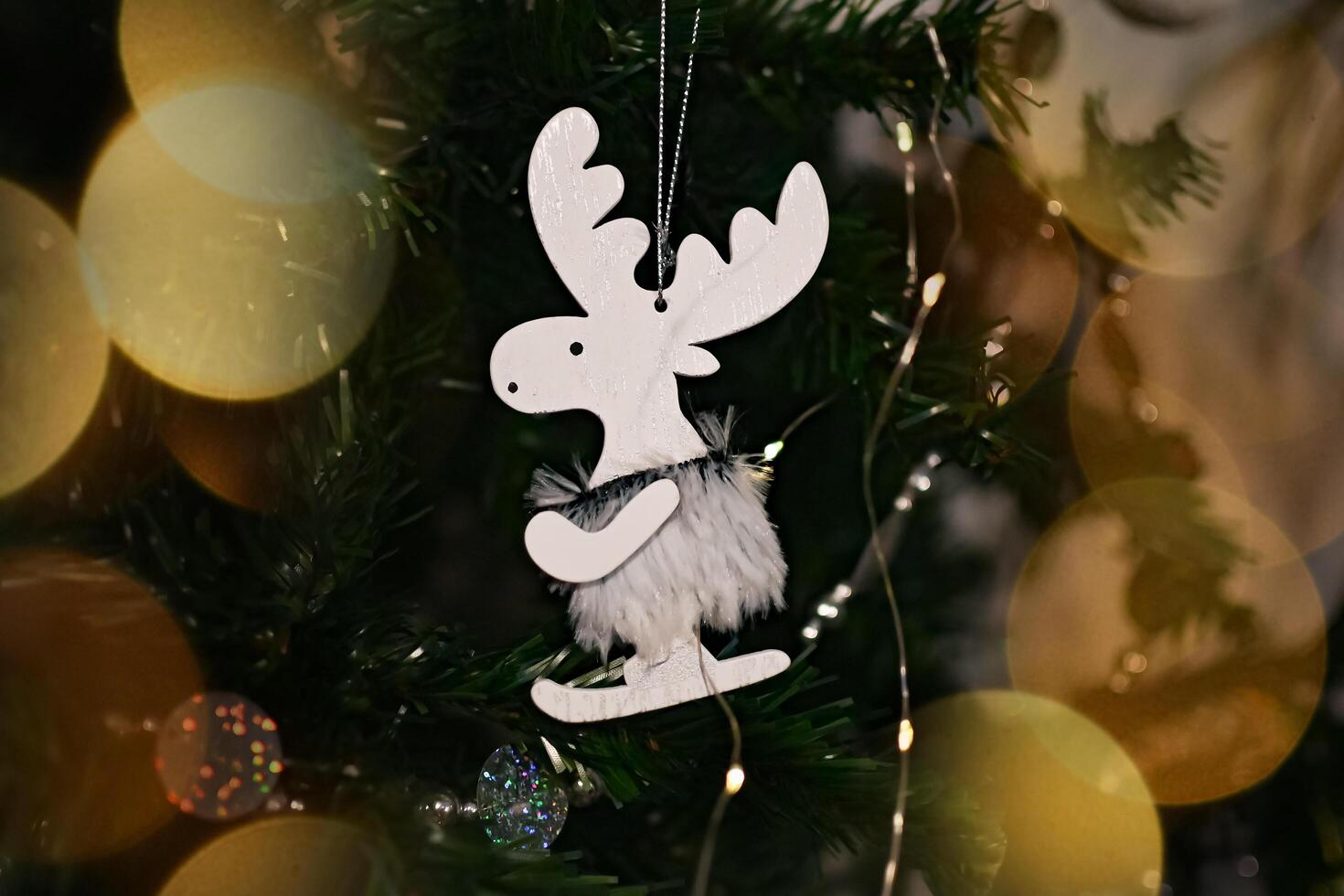 New Year and Christmas greeting card with a deer. A hand holds a deer toy near the Christmas tree. photo