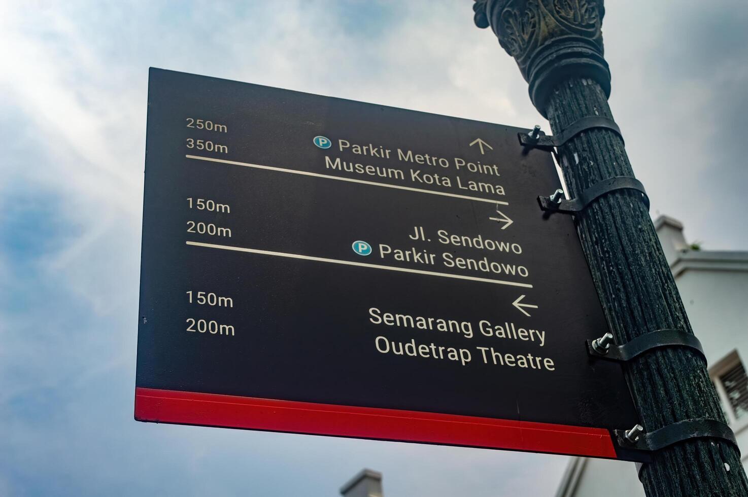 A directional signpost in Semarang points to local attractions and parking areas, including Parkir Metro Point and Museum Kota Lama, Indonesia, 16 November 2024. photo