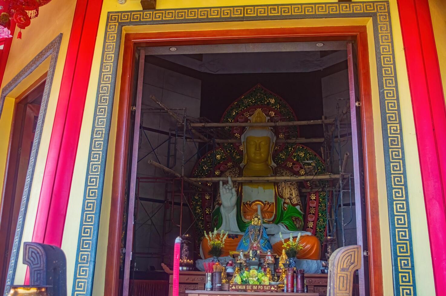 A vibrant temple entrance adorned with intricate patterns and a large statue under renovation, featuring offerings and decorations for Lunar New Year celebrations, Indonesia, 17 November 2024 photo