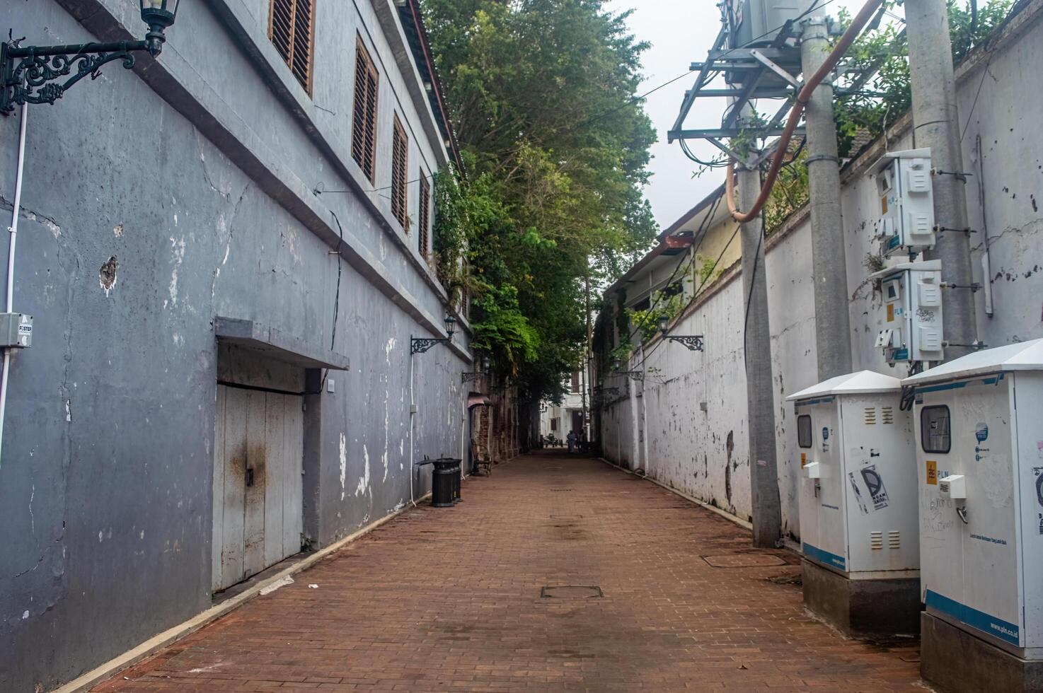 A narrow alleyway in Kota Tua Semarang, featuring weathered buildings and electrical infrastructure, Indonesia, 16 November 2024 photo