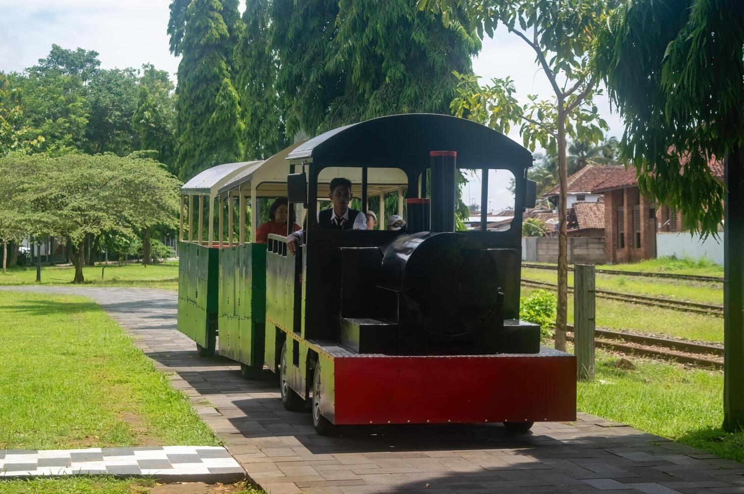 A kiddie train rides through a lush park, offering a scenic and enjoyable experience for children and families. Indonesia, 17 November 2024 photo