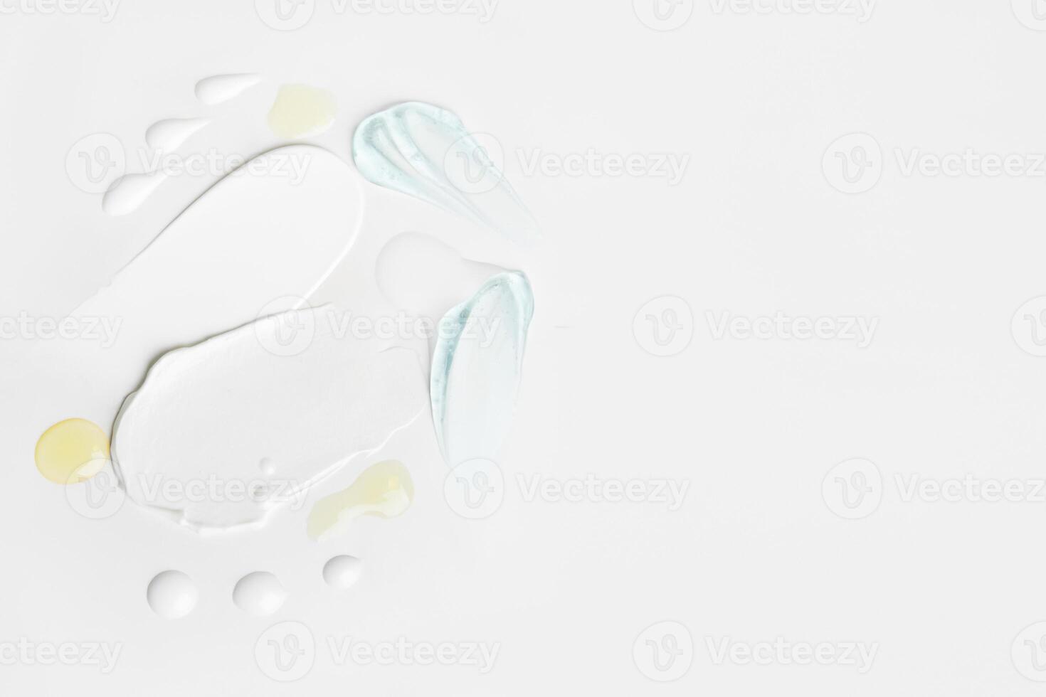 Beauty textures including cream smears, yellow drops, and blue gel details on a light surface with space for customization. photo