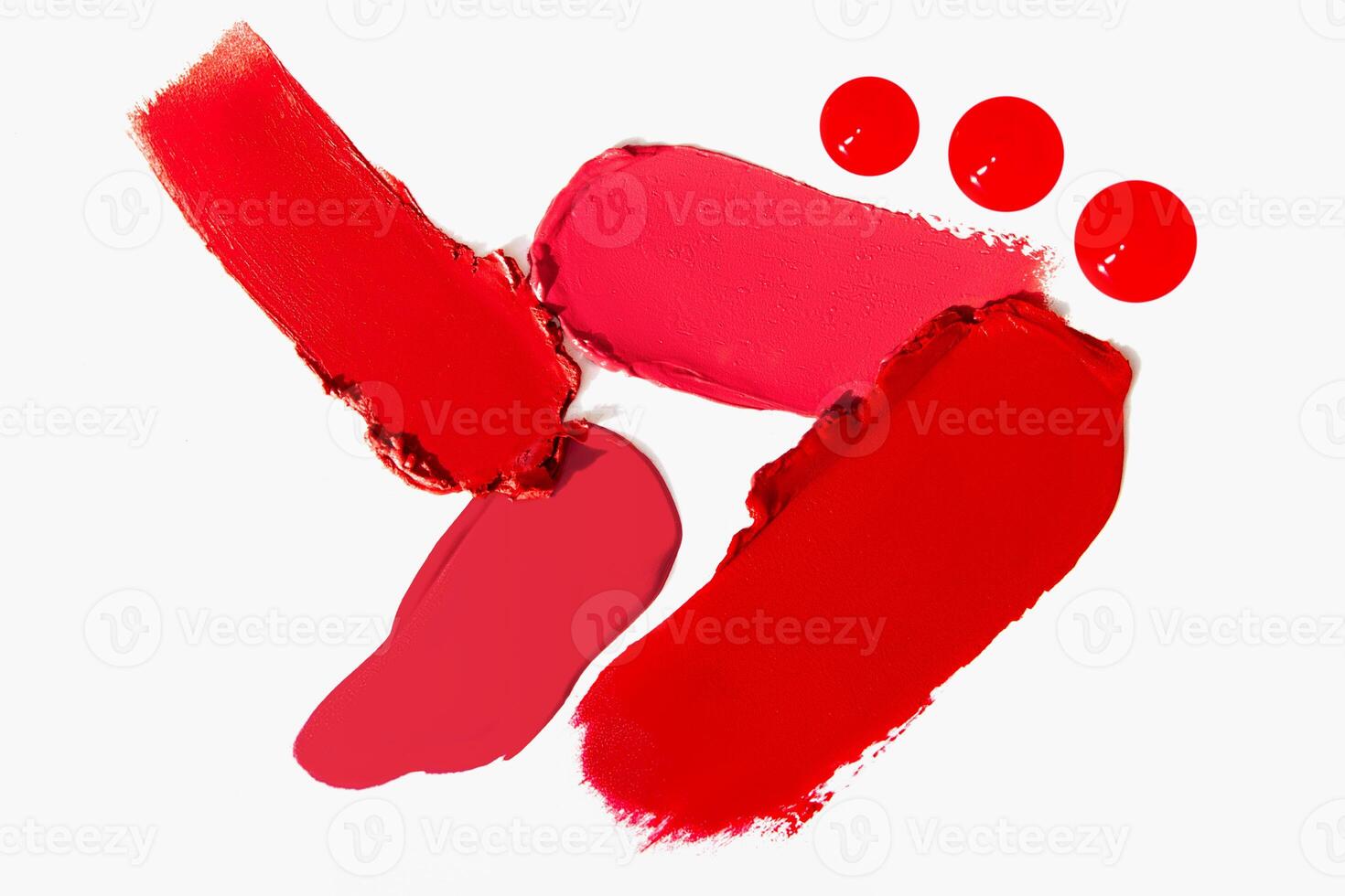 Cosmetic texture of lipstick smears in a variety of red shades on a light white background. Beauty product stroke swatch. photo