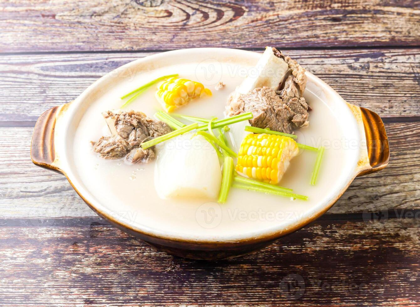 Radish and Pork Bone Pot with corn and scallions served in broth isolated on wooden table side view of hong kong food photo