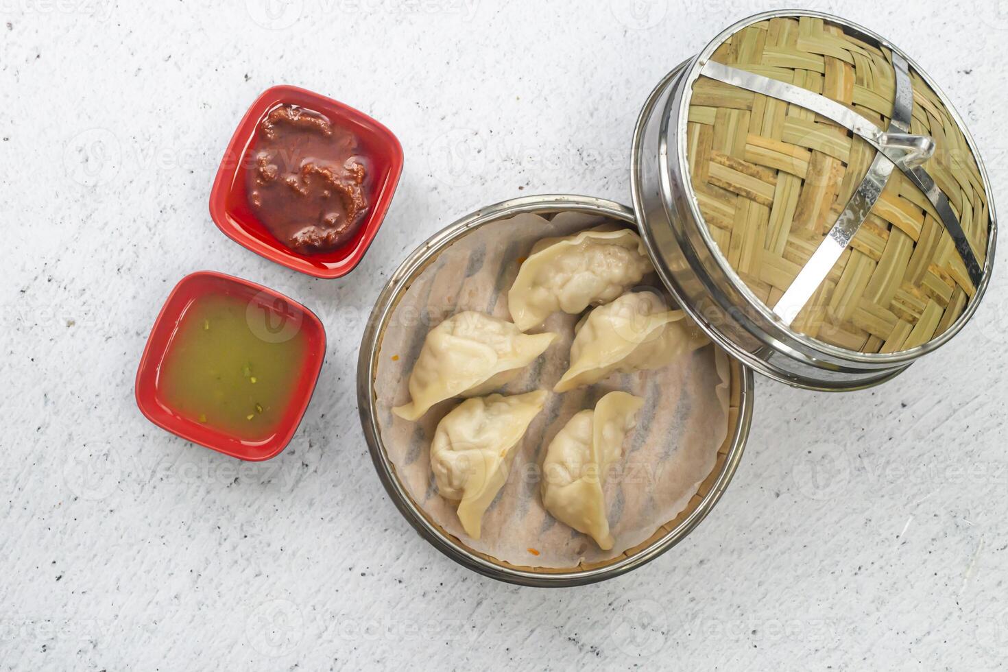 Steamed Chicken Cheese Mushroom Momo or Dumplings with mayo dip and tomato sauce served in bamboo steamer isolated on white background top view of bangladeshi, indian and chinese dim sum food photo
