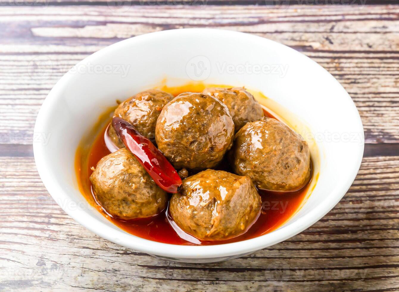 Braised Spicy beef tendon balls served in bowl isolated on wooden table side view of hong kong food photo