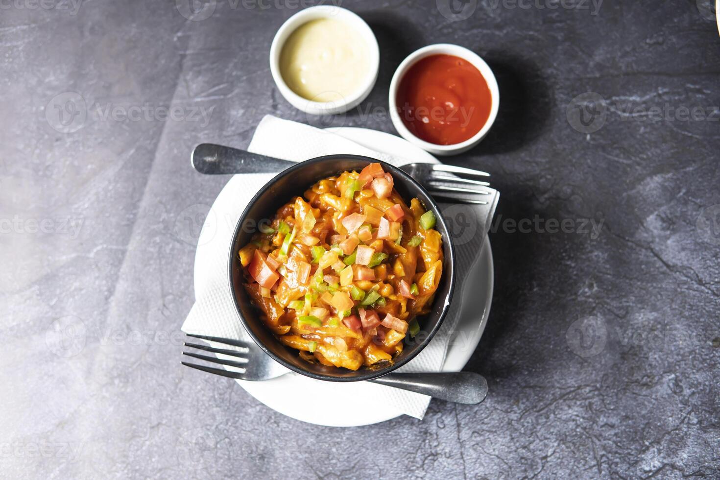 Red Chili and tomato Pasta with ketchup, mayo dip and fork served in bowl dish isolate on grey background top view of indian, bangladeshi and pakistani food photo