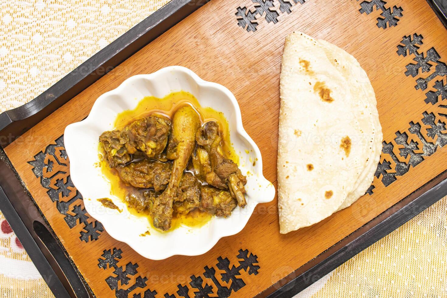 Spicy Desi Chicken Curry with Roti served on tray dish isolated on dinning table top view of bangladeshi food photo