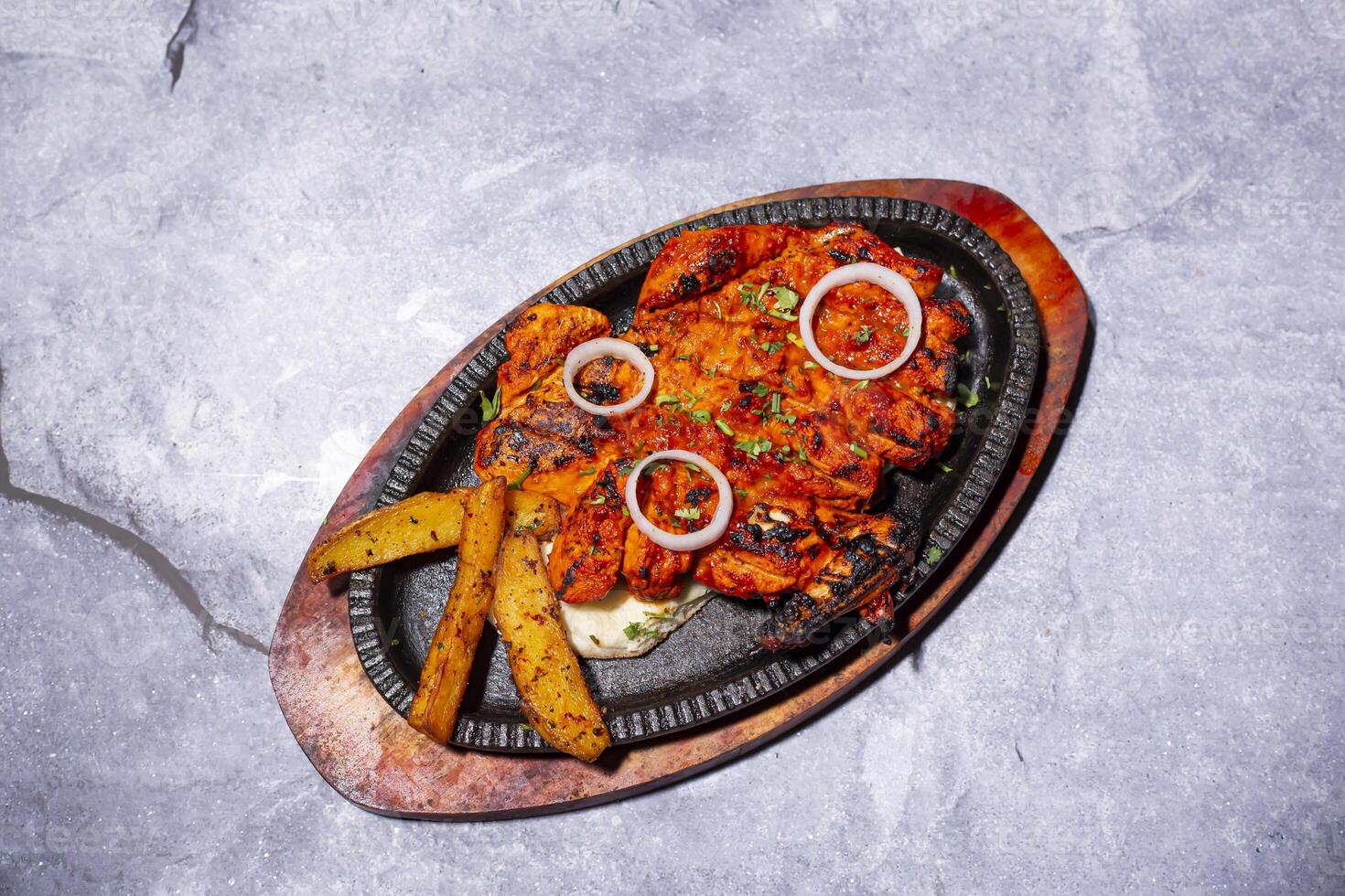 Chicken Tikka Kebab with onion, fries, nan, and bread served on a sizzling plate isolated on grey background side view of indian, bangladeshi and pakistani bbq food photo
