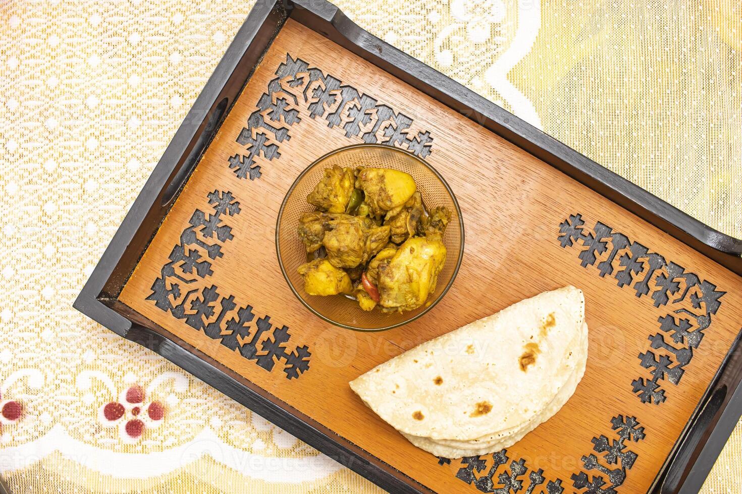 Spicy fried chicken with roti served on tray dish isolated on dinning table top view of bangladeshi food photo