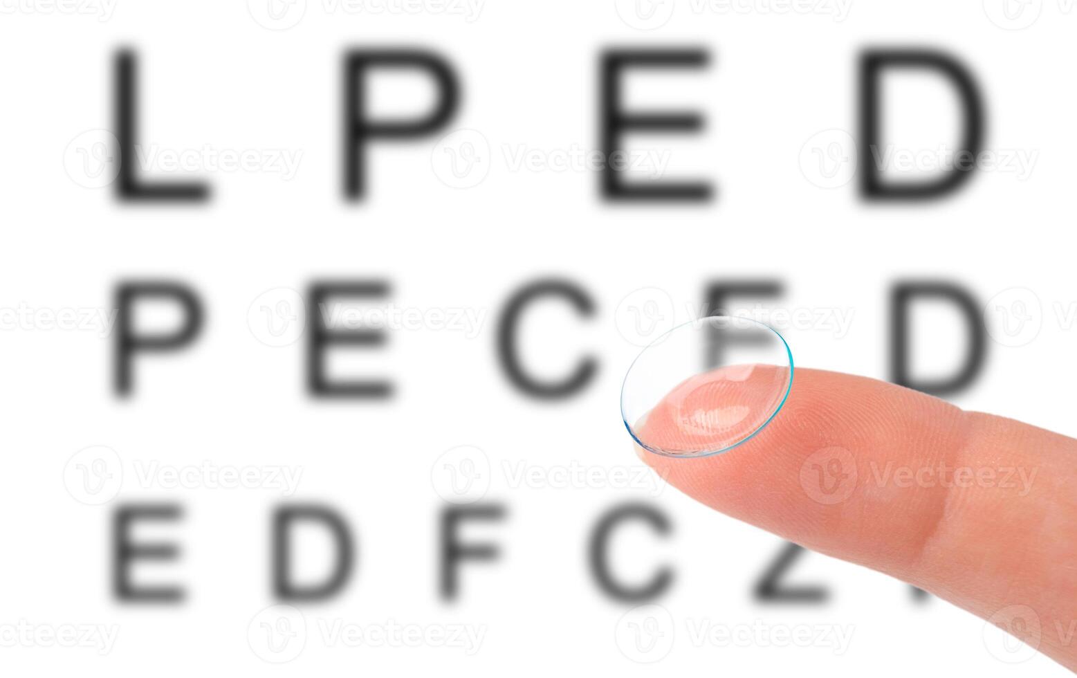 Contact lens on finger and snellen eye chart. The eye test chart is shown blurred in the background photo
