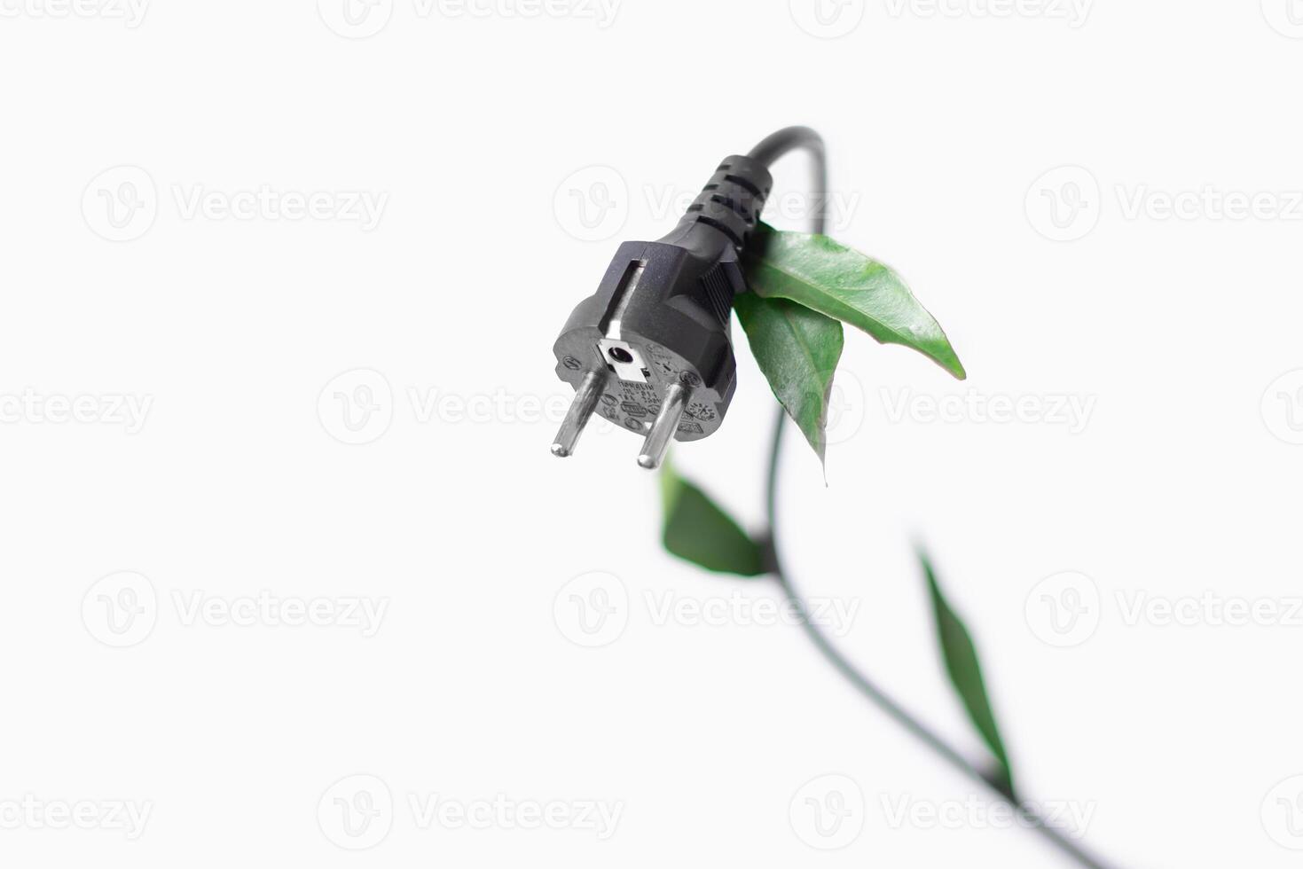 Power plug with green leaves into power outlet against a white background with copy space photo
