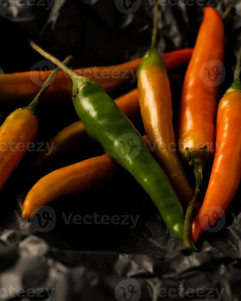 yellow and green chili peppers lie on black craft paper photo