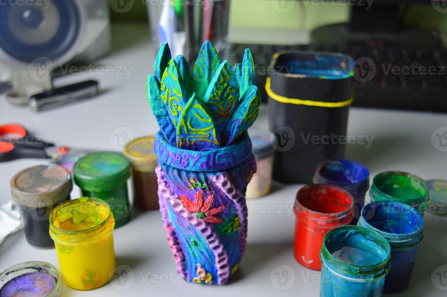 A beautiful ceramic vase vessel in boho marine style after being painted with acrylic and gouache stands to dry on a table in a pottery workshop. High quality photo