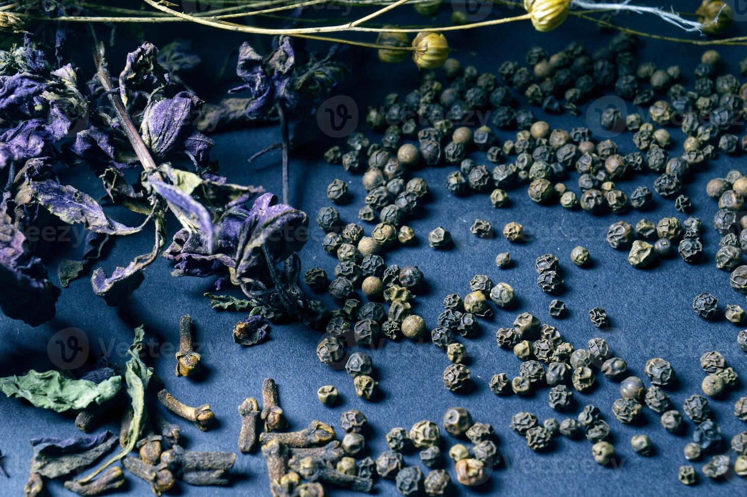 various spices scattered on a dark background with bunches of grass, laurel leaves, berries and other spices for cooking fragrant Eastern and Midwestern food. High quality photo