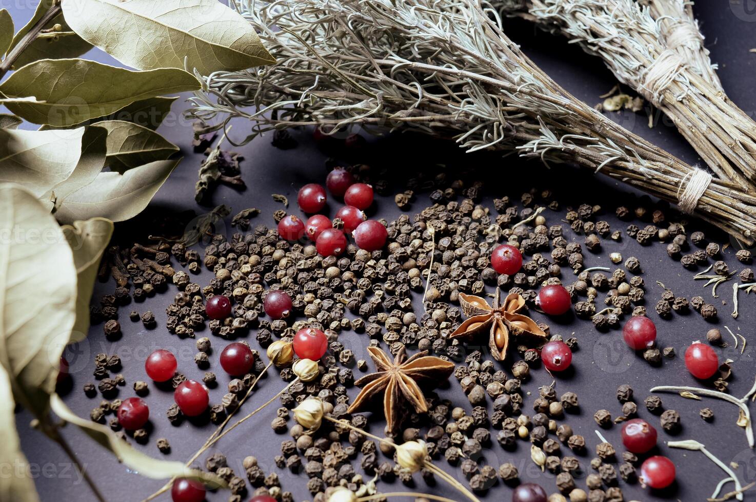 various spices scattered on a dark background with bunches of grass, laurel leaves, berries and other spices for cooking fragrant Eastern and Midwestern food. High quality photo