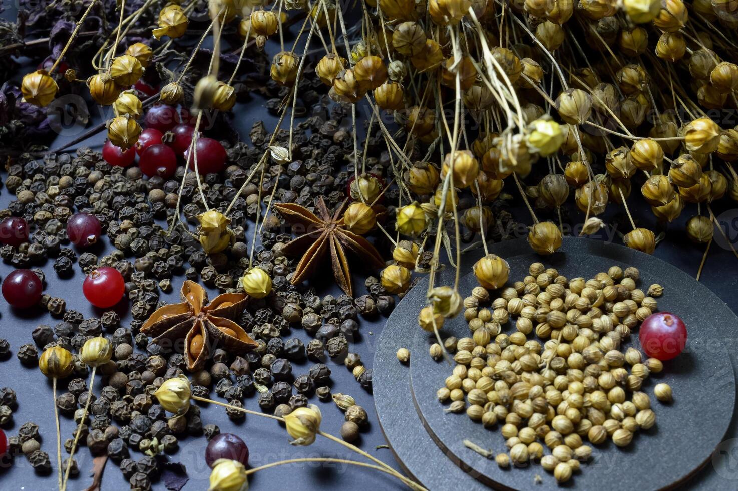 various spices scattered on a dark background with bunches of grass, laurel leaves, berries and other spices for cooking fragrant Eastern and Midwestern food. High quality photo