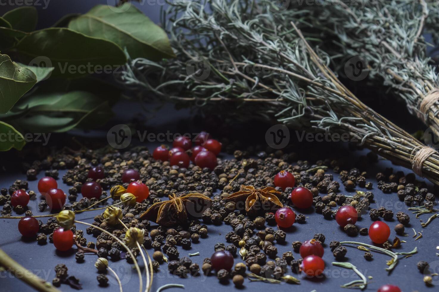 various spices scattered on a dark background with bunches of grass, laurel leaves, berries and other spices for cooking fragrant Eastern and Midwestern food. High quality photo