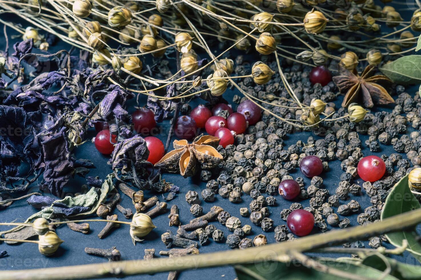 various spices scattered on a dark background with bunches of grass, laurel leaves, berries and other spices for cooking fragrant Eastern and Midwestern food. High quality photo