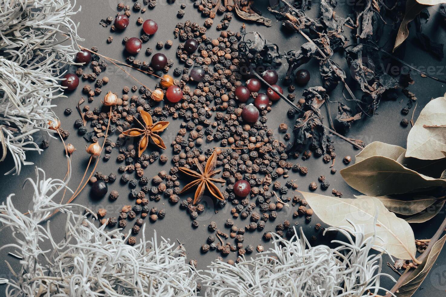 various spices scattered on a dark background with bunches of grass, laurel leaves, berries and other spices for cooking fragrant Eastern and Midwestern food. High quality photo