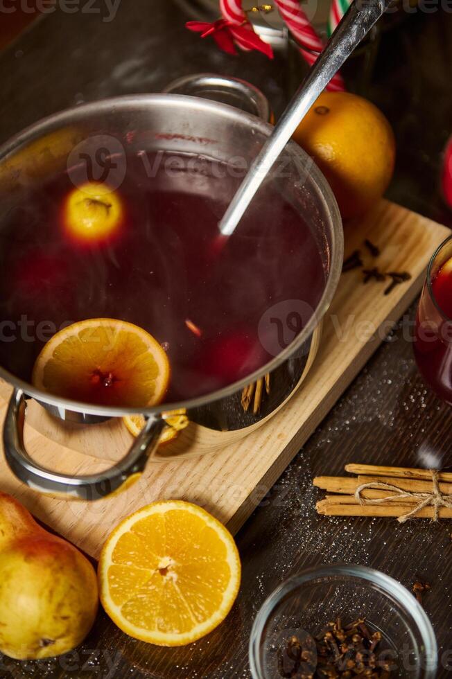 Warm mulled wine with spices and citrus slices served in a pot photo