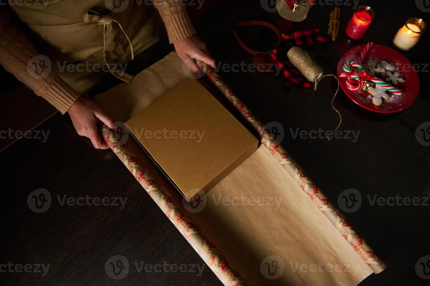 Wrapping a present with Christmas decorations by candlelight on a cozy evening photo