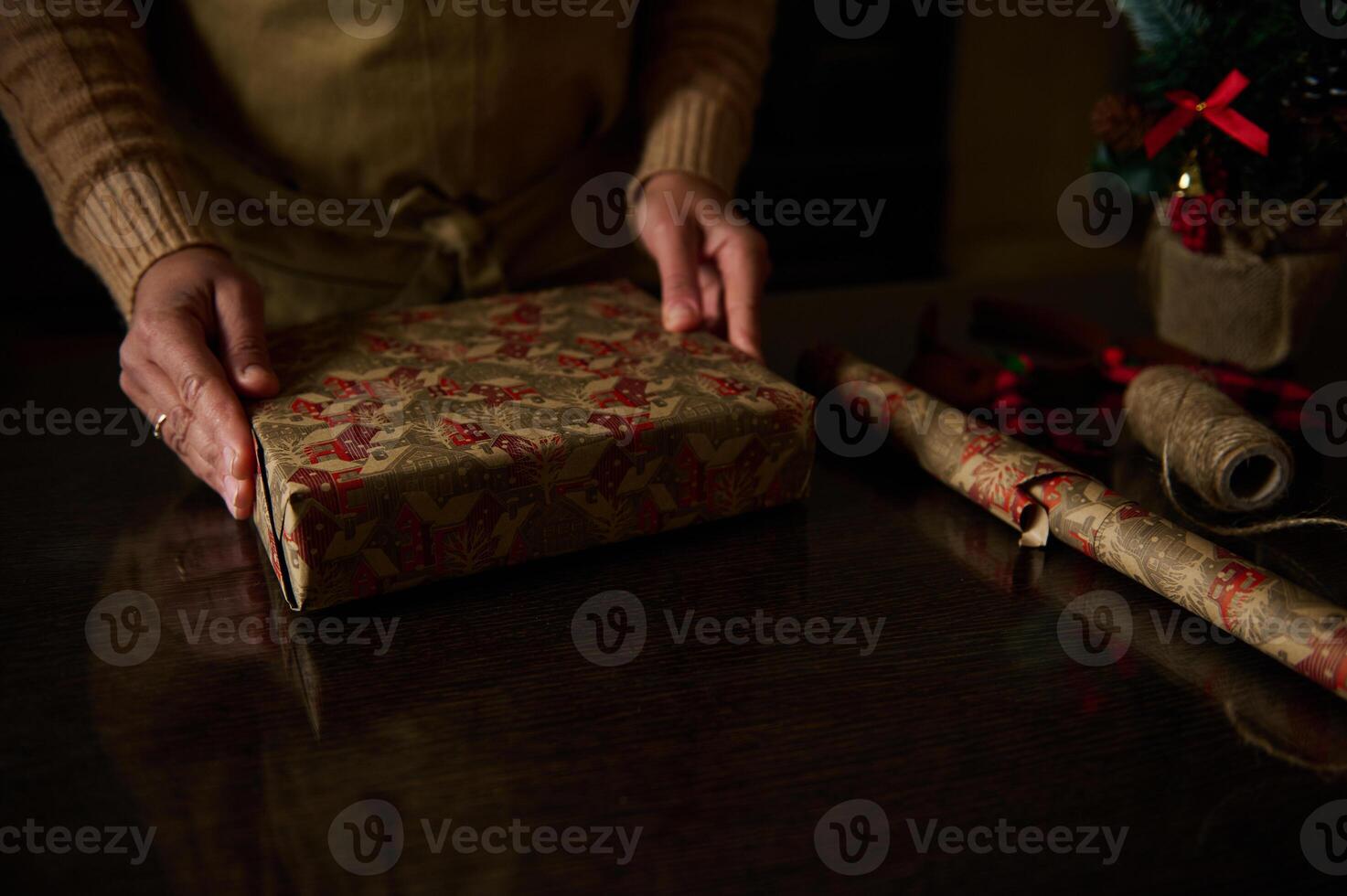 Hands carefully wrapping a holiday gift with festive paper on a table photo